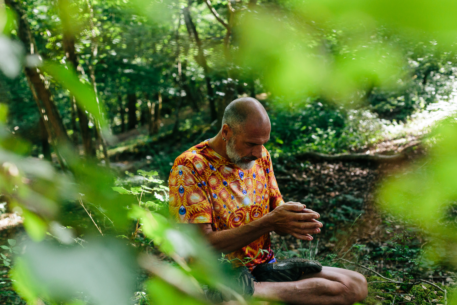 Christopher Gladwell sitting in woodland with hands in prayer position